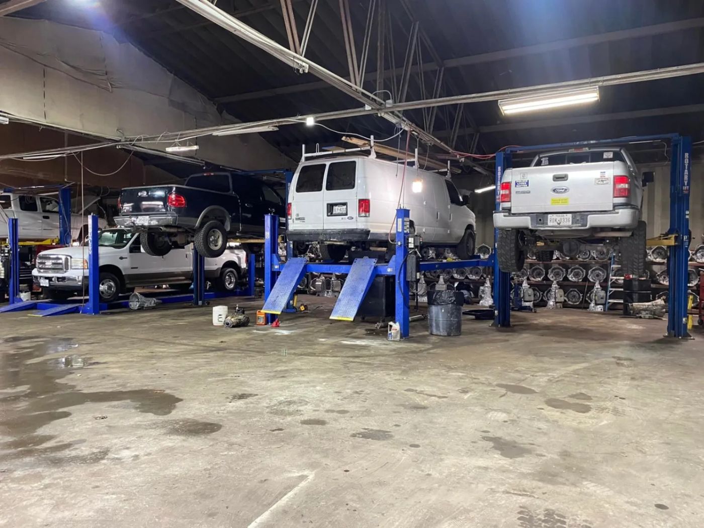 Ford trucks and a work van up on the lifts at Arevalo's Auto Repair in Irving, Texas